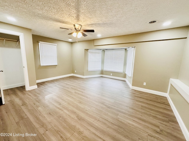 unfurnished bedroom with ceiling fan, a textured ceiling, and light wood-type flooring