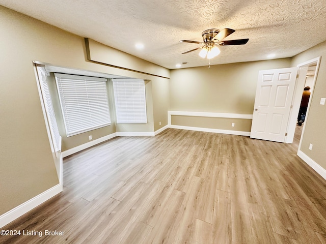 empty room with ceiling fan, a textured ceiling, and light hardwood / wood-style flooring