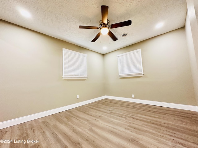 spare room with ceiling fan, light wood-type flooring, and a textured ceiling