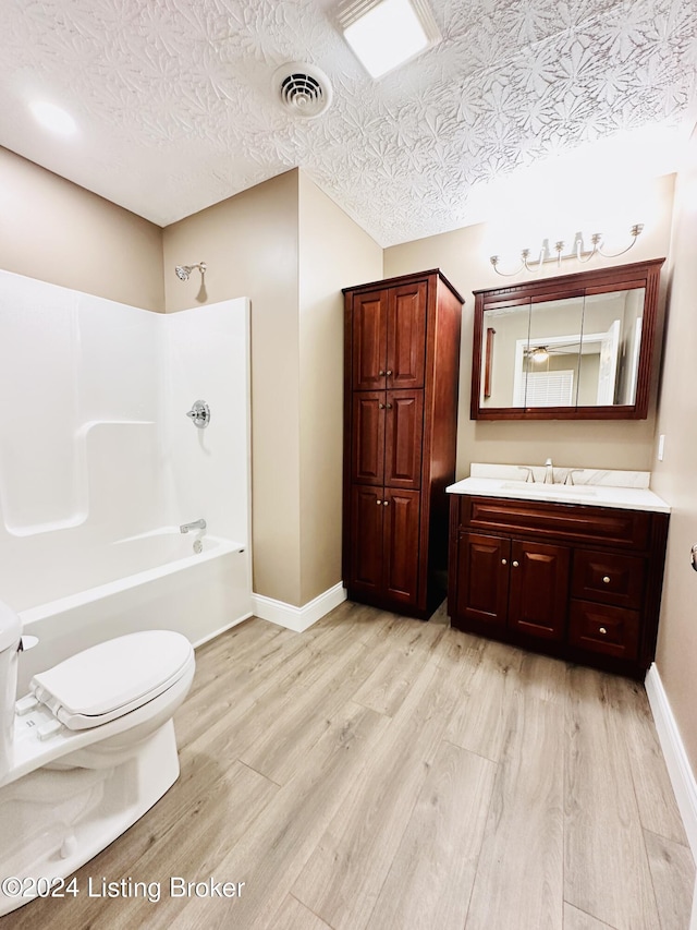 full bathroom featuring bathtub / shower combination, a textured ceiling, vanity, hardwood / wood-style floors, and toilet