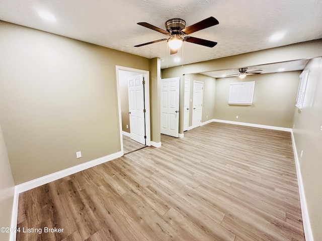 empty room featuring ceiling fan, a textured ceiling, and light wood-type flooring