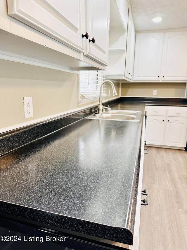 kitchen featuring white cabinetry, sink, and light wood-type flooring