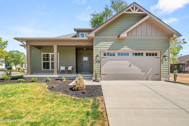 view of front of property featuring covered porch, a front yard, and a garage