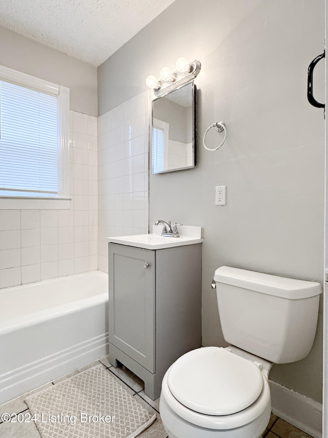 full bathroom featuring vanity, tile patterned flooring, tiled shower / bath combo, toilet, and a textured ceiling