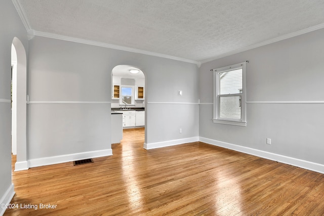 spare room with crown molding, sink, a textured ceiling, and light hardwood / wood-style flooring