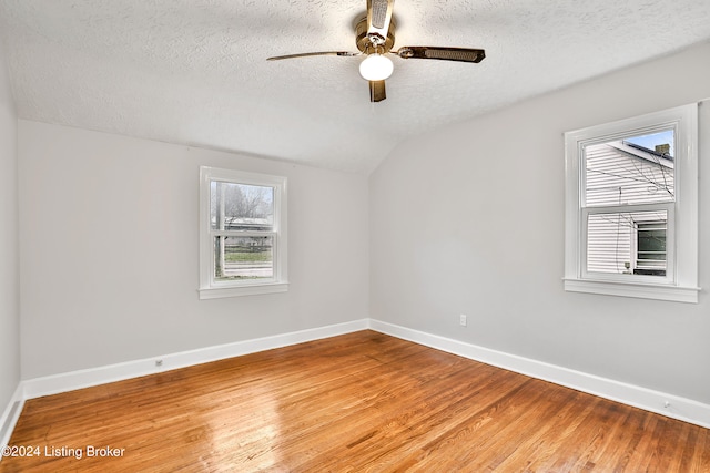 spare room featuring hardwood / wood-style flooring, ceiling fan, a textured ceiling, and vaulted ceiling