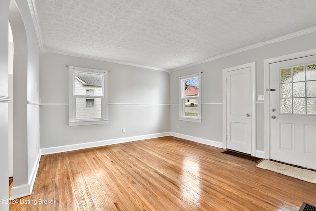 foyer entrance with a textured ceiling, light hardwood / wood-style floors, and crown molding