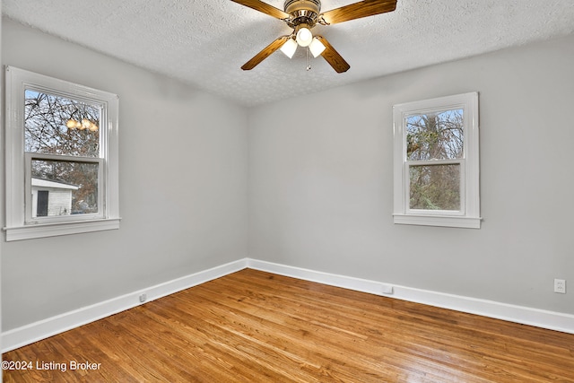 unfurnished room with hardwood / wood-style floors, ceiling fan with notable chandelier, and a textured ceiling