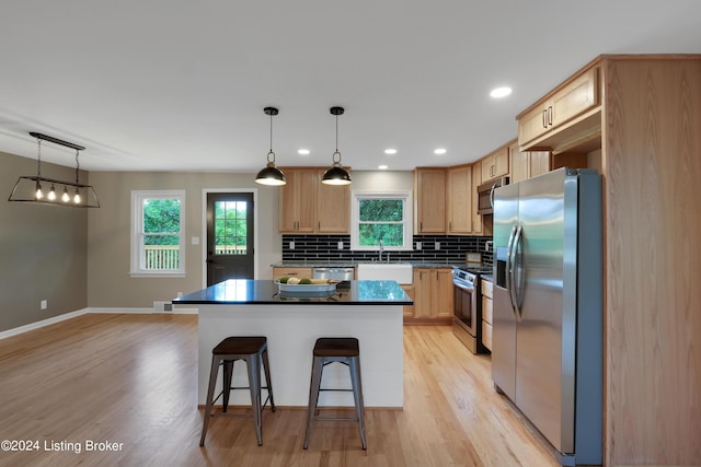 kitchen with backsplash, a kitchen bar, hanging light fixtures, a center island, and stainless steel appliances