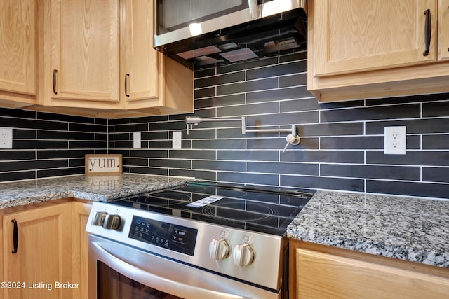 kitchen featuring tasteful backsplash, appliances with stainless steel finishes, light brown cabinets, and light stone counters