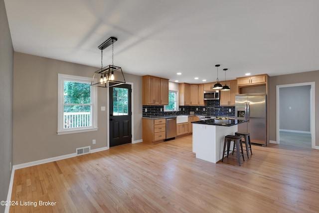 kitchen with stainless steel appliances, a kitchen island, pendant lighting, and a kitchen bar