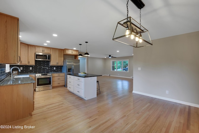 kitchen featuring sink, hanging light fixtures, a center island, light hardwood / wood-style floors, and stainless steel appliances