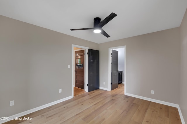 unfurnished bedroom with ceiling fan, connected bathroom, a spacious closet, and light wood-type flooring