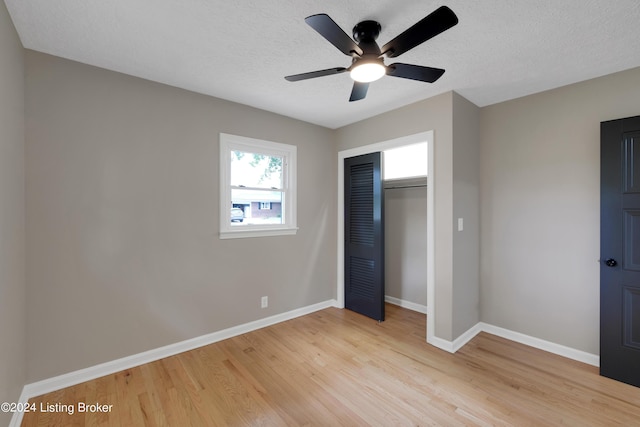 unfurnished bedroom with ceiling fan, light hardwood / wood-style floors, a closet, and a textured ceiling