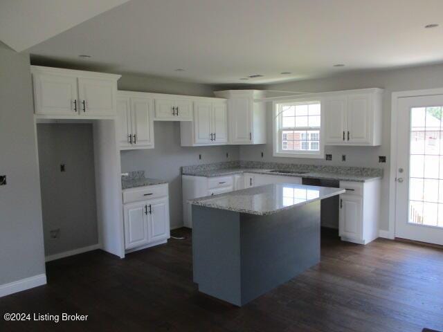 kitchen with dark hardwood / wood-style flooring, a kitchen island, light stone counters, and white cabinetry