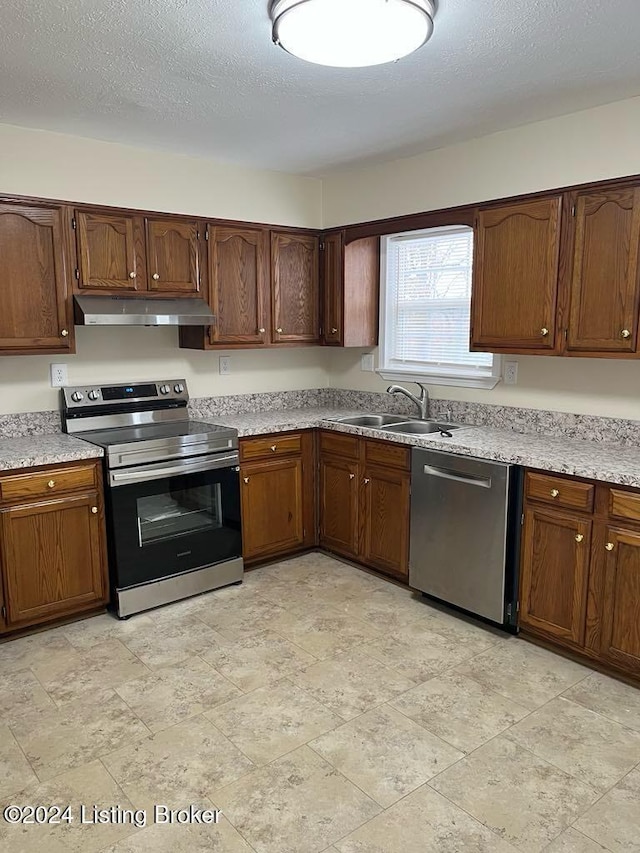 kitchen with a textured ceiling, sink, and stainless steel appliances