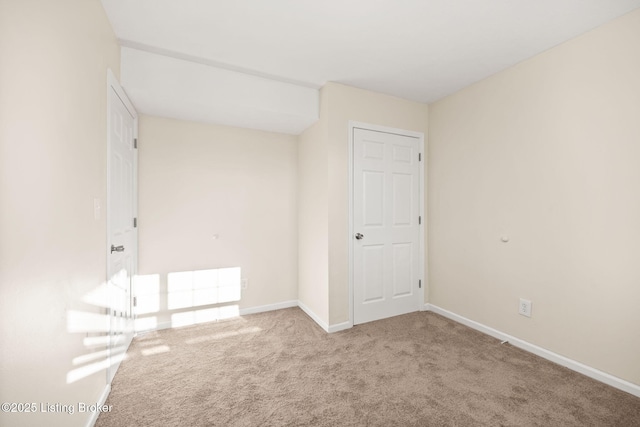 carpeted empty room featuring baseboards