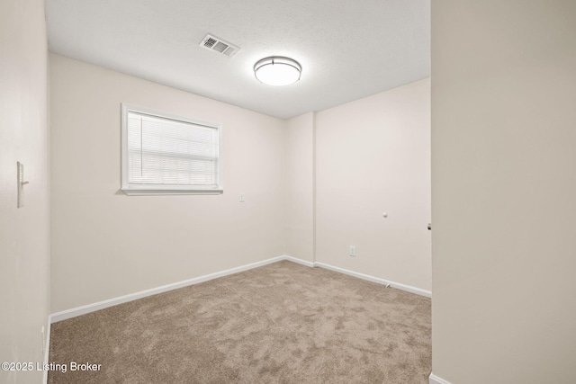 carpeted empty room featuring visible vents, baseboards, and a textured ceiling