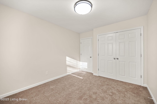 unfurnished bedroom with carpet flooring, baseboards, and a closet