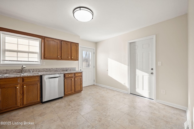 kitchen featuring brown cabinets, a sink, light countertops, baseboards, and dishwasher