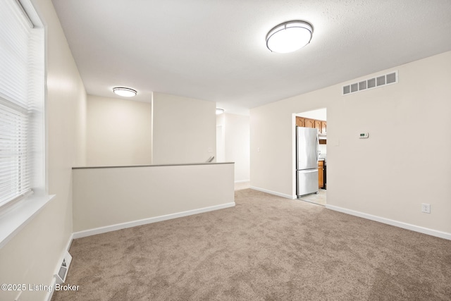 empty room with visible vents, light carpet, and baseboards