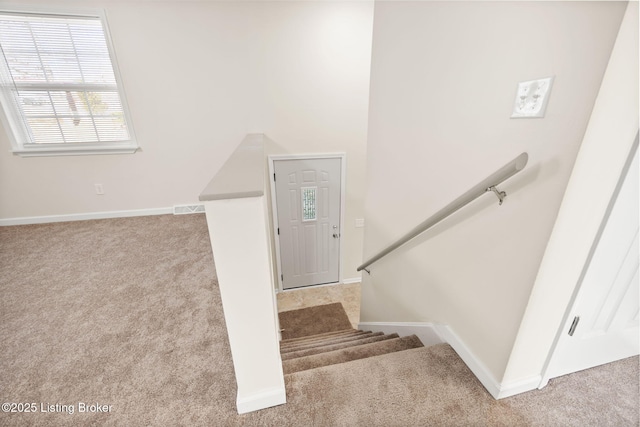 staircase with visible vents, baseboards, and carpet flooring