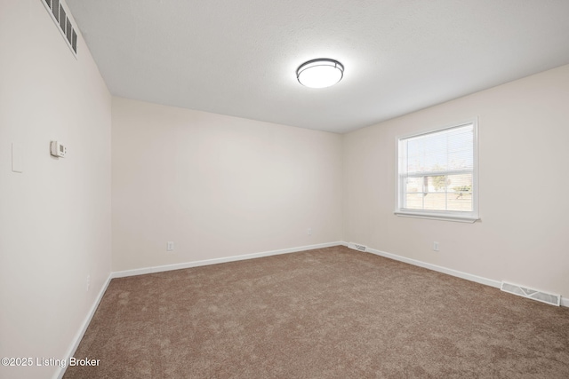 carpeted spare room featuring baseboards and visible vents