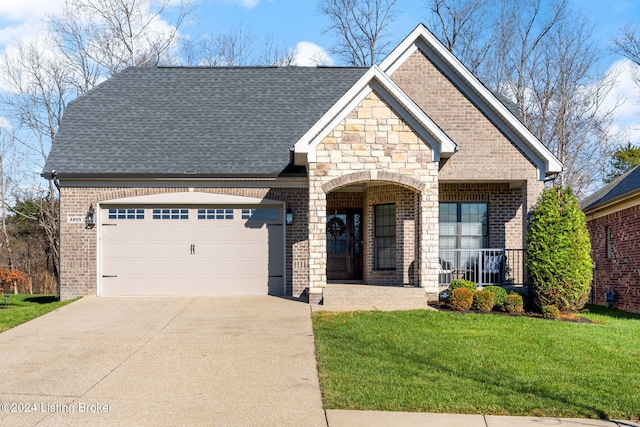 view of front of home featuring covered porch, a garage, and a front yard