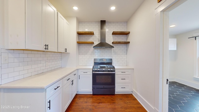 kitchen featuring wall chimney range hood, white cabinets, tasteful backsplash, and stainless steel gas range