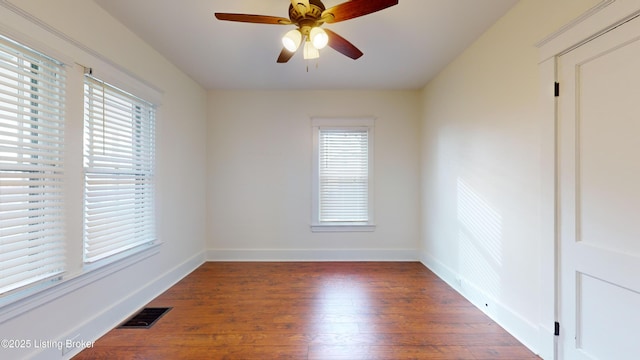 spare room with plenty of natural light, ceiling fan, and dark wood-type flooring