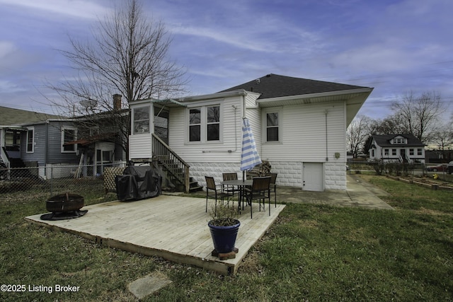 rear view of house with a wooden deck, a yard, and an outdoor fire pit