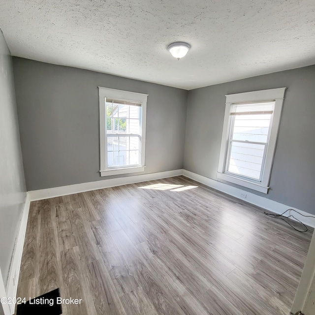 spare room with light hardwood / wood-style flooring and a textured ceiling