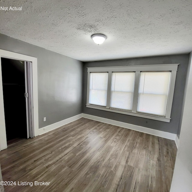 unfurnished room featuring dark wood-type flooring and a textured ceiling