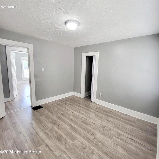 unfurnished room featuring a textured ceiling and light hardwood / wood-style floors