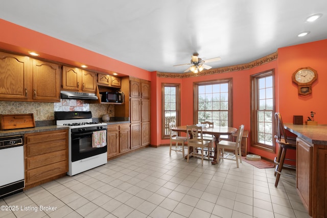 kitchen with decorative backsplash, light tile patterned flooring, white appliances, and ceiling fan