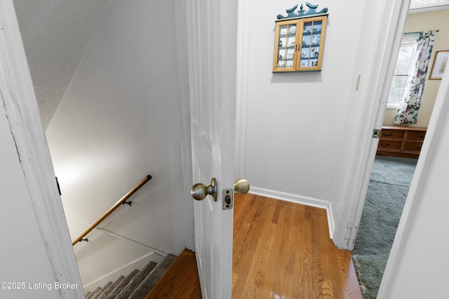 stairway with hardwood / wood-style floors and a textured ceiling