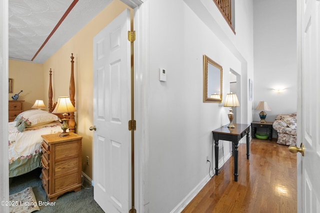 corridor featuring hardwood / wood-style flooring, a textured ceiling, and vaulted ceiling