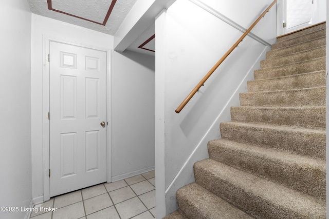 staircase featuring tile patterned flooring and a textured ceiling