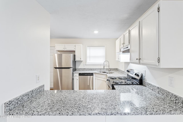 kitchen with light stone counters, stainless steel appliances, white cabinetry, and sink