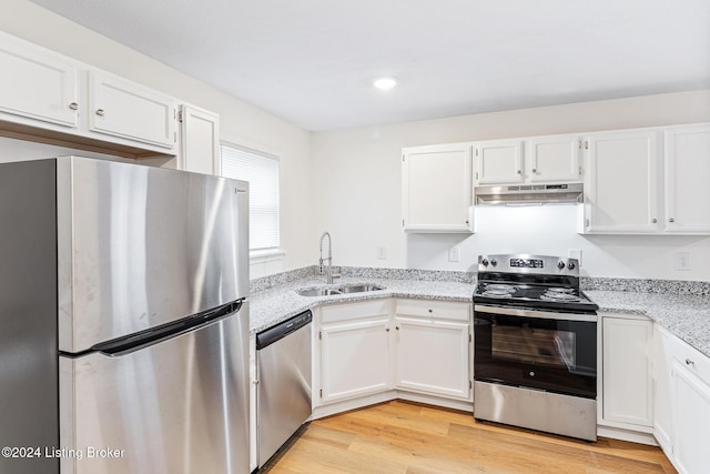 kitchen with light stone countertops, white cabinetry, sink, stainless steel appliances, and light hardwood / wood-style flooring