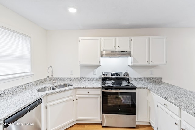 kitchen featuring white cabinetry, sink, light stone countertops, appliances with stainless steel finishes, and light wood-type flooring