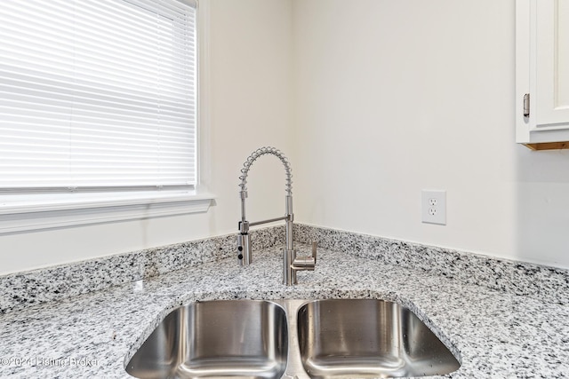 room details featuring light stone counters, white cabinetry, and sink