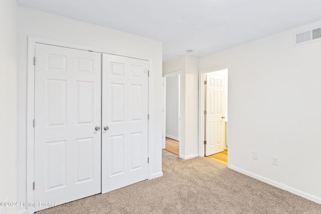 unfurnished bedroom with light carpet and a closet