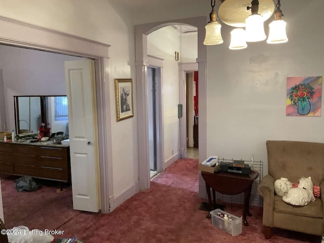 hallway with carpet flooring and a notable chandelier