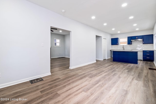 unfurnished living room with ceiling fan, a healthy amount of sunlight, sink, and light hardwood / wood-style flooring