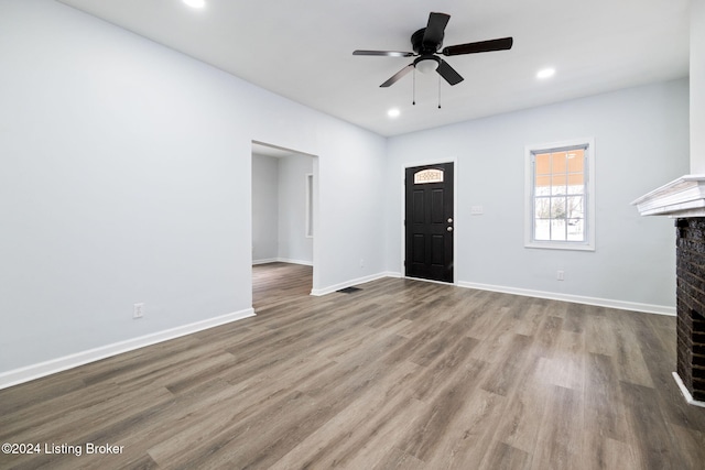 entrance foyer with hardwood / wood-style flooring, ceiling fan, and a fireplace