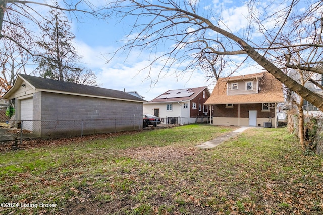 rear view of house featuring central air condition unit, a yard, an outdoor structure, and a garage