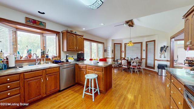 kitchen featuring lofted ceiling, sink, stainless steel dishwasher, light wood-type flooring, and decorative light fixtures