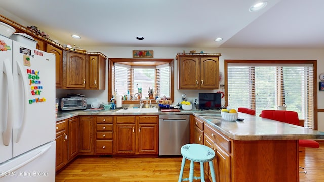 kitchen with stainless steel dishwasher, a breakfast bar, sink, light hardwood / wood-style flooring, and white fridge