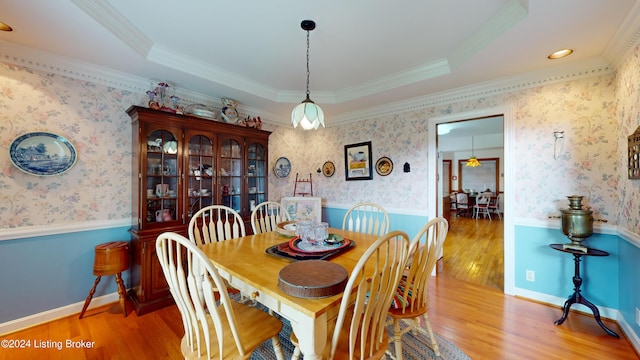 dining room with a raised ceiling, crown molding, and hardwood / wood-style flooring